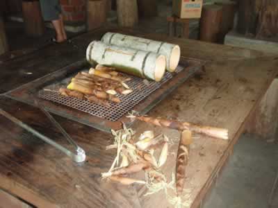 Bamboo shoots and rice boiling in bamboo sections on barbecue grill