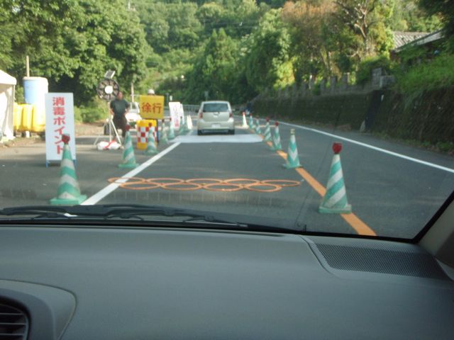 Mountain Roads have plastic Speed bumps and several workers overseeing drivers as they pass among traffic cones to pass over disinfectant mats at 10 km per hour.